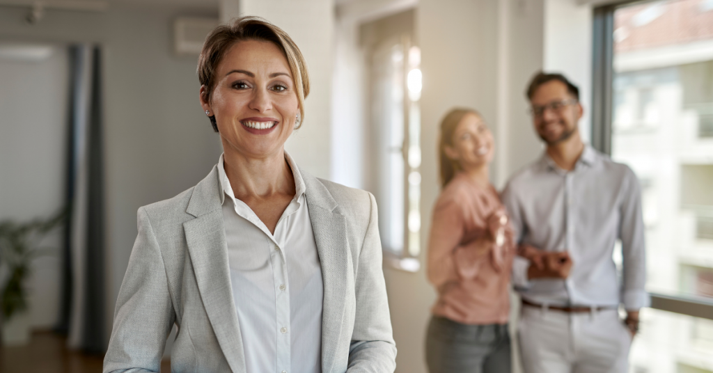 Picture showing a smiling friendly estate agent with a happy couple in the background